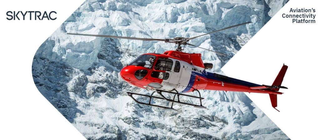 An emergency medical services helicopter flying in front of a snowy mountain